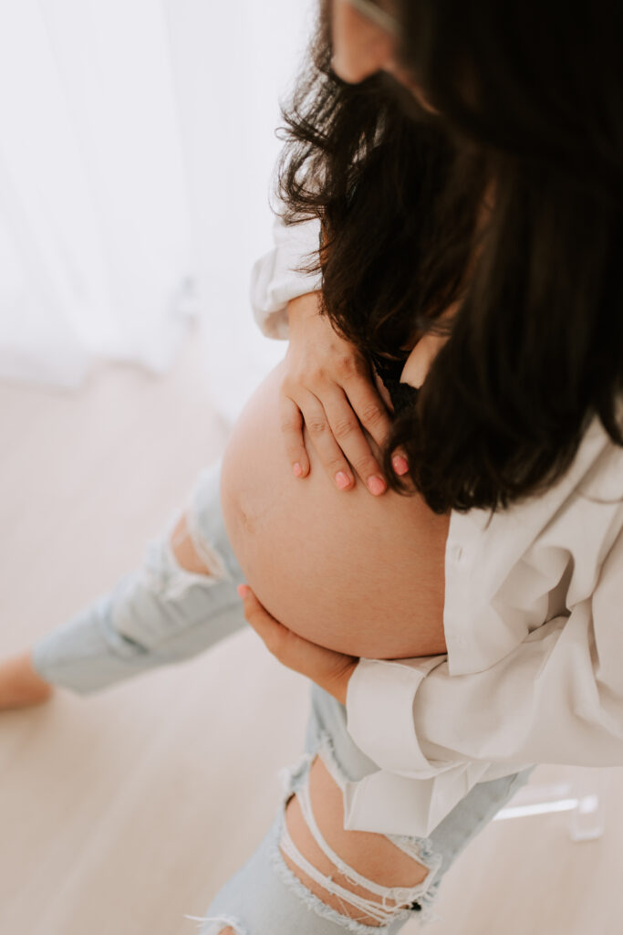 pregnant mom holding her belly at a studio in Roanoke, TX during a motherhood photography event